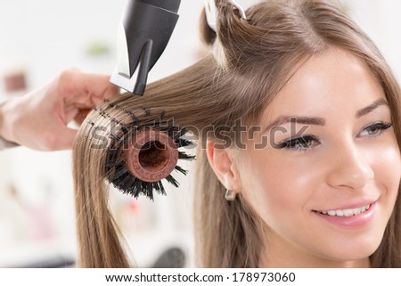 Hairdresser drying long brown hair with hair dryer and round brush. Close-Up. Royalty-Free Stock Photo #178973060
