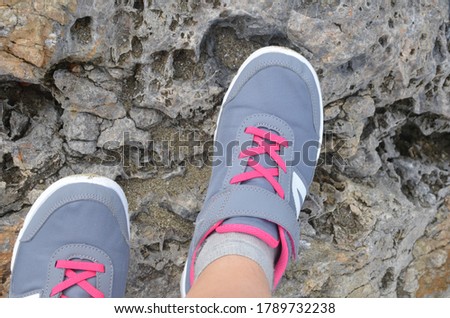 Mood photo of legs wearing sportive hiking shoes with strong protective sole. legs in trekking footwear for mountain travel standing on stone outdoor at nature on abstract background