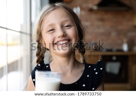 Close up headshot portrait of happy little preschooler girl with white moustache from drinking tasty nutritional milk, smiling small child kid laugh taste delicious organic lactose free yoghurt