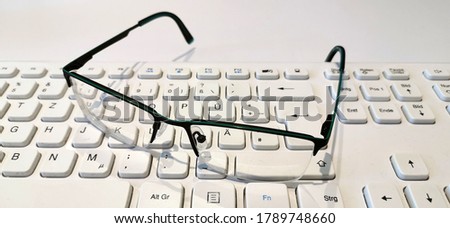 A white keyboard with glasses lying on it