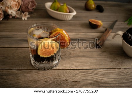 Figs and blackberries in cold water in glass on old table