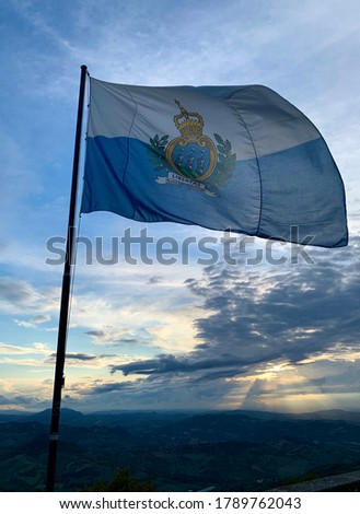 Flag of San Marino Republic on a cloudy sunset background