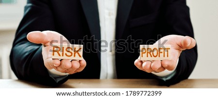 risk profit. man offers a choice of wooden blocks with the words risk and profit