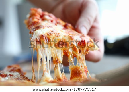 Male arm taking slice of cheesy tasty fresh pizza close-up