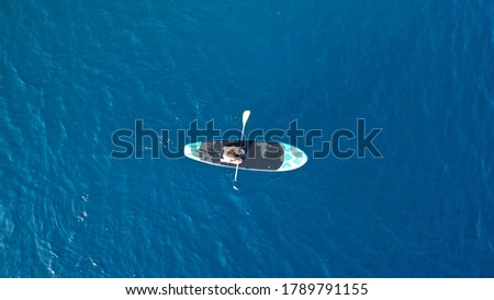 Aerial photo of fit woman paddling on a sup board in deep blue Aegean sea