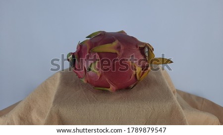 The pink dragon fruit is placed on a brown cloth, the background is white.
