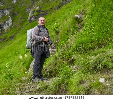 Professional nature photographer with camera and big backpack hiking into the highlands