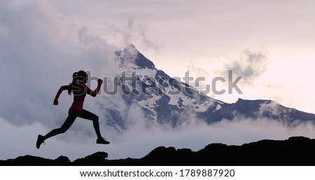 Running woman athlete sport concept. Trail runner exercising in mountain summit background. Female runner on run training outdoors living active fit lifestyle. Silhouette at sunset.