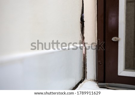 Cracked cement wall in the house,cracking separation of the concrete wall texture from subsidence ground,problems with non-standard home renovations,repair or house extension of substandard buildings Royalty-Free Stock Photo #1789911629