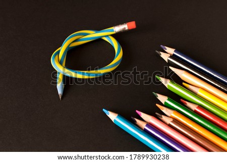 Flexible pencil and a set of colored pencils on a dark background. Selective focus