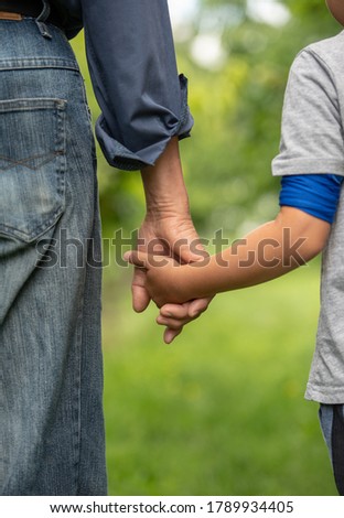 2 generation men are walking hand in hand on green grass Royalty-Free Stock Photo #1789934405