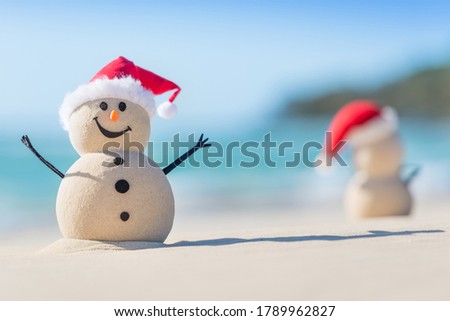 Two Sandy Christmas Snowmen are celebrating Christmas on a beautiful beach, one of them is only in focus