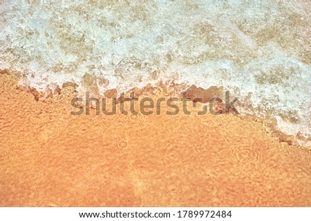 Sea wave on the sand beach, soft focus. Summer background. Waves with splashes and foam. 