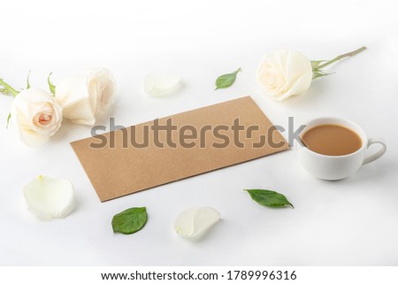 Flowers romantic composition. Morning coffee mug for breakfast, empty notebook with copy space for text or lettering and white roses. Female blogger workplace. backlight
