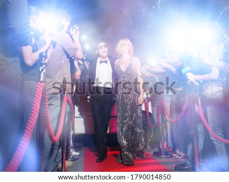 Celebrity couple arriving a premiere with paparazzi cameras and flashes Royalty-Free Stock Photo #1790014850