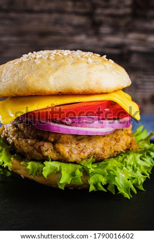 Fresh delicious homemade veggie burger lies on natural slate on rustic wooden background. Delicious tasty burger with lettuce, cheese, onion and tomato. buckwheat and lentil cutlet