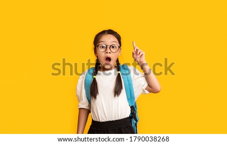 Asian Nerdy Schoolgirl Pointing Finger Up Having Great Idea Standing Over Yellow Studio Background. Eureka Concept