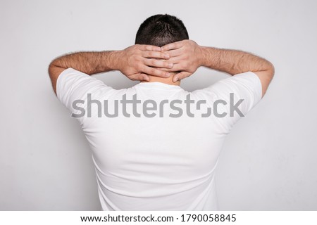 the guy is a brunette with a wide back and is wearing a white t-shirt.
rear view. a man on a white background in home casual clothes. concept: men's health, problems with the collar spine, neck pain Royalty-Free Stock Photo #1790058845