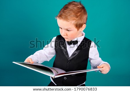 Little boy reading a book on a green background.