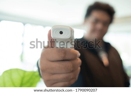 Man carrying digital Infrared thermometer with blur background
