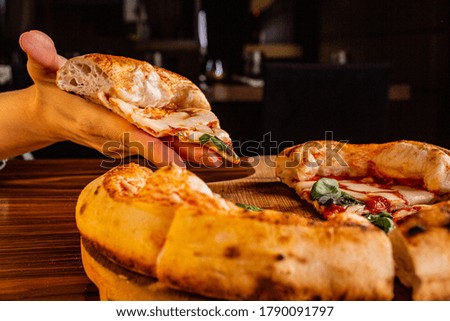 Hand holding a slice of margherita pizza