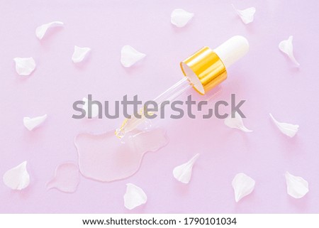 Cosmetic pipette with oil on pink background close-up. Around - flower petals. Stylish concept of organic essences, beauty and health products. Copy space, minimalism, flat lay. Modern apothecary. 