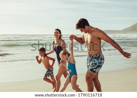 Beautiful family having a great on the  summer vacation. Happy mother and father with their kids having fun during summer holiday on beach.