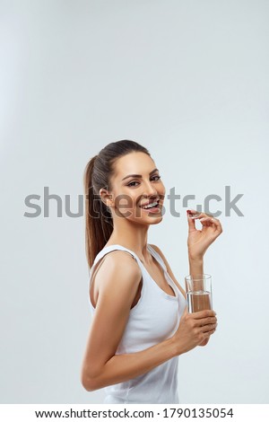 Happy Smiling Woman Taking Pill With Cod Liver Oil Omega-3 And Holding A Glass Of Fresh Water In Morning. Vitamin D, E, A Fish Oil Capsules. Diet. Nutrition. Healthy Eating Royalty-Free Stock Photo #1790135054