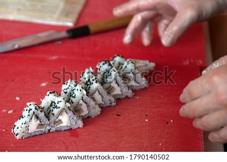 Pieces of sushi with triangular-shaped tomago olmet on a kitchen board, close-up.