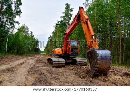 Excavator clearing forest for new development. Orange Backhoe modified for forestry work. Tracked heavy power machinery for forest and peat industry. Logging, road construction in forests Royalty-Free Stock Photo #1790168357