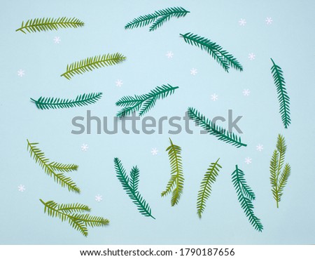Handmade paper art Christmas spruce branch. On blue background with snowflake. Cutout. Frame for your design. 