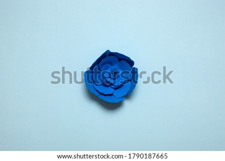 Set of handmade paper art and cutout flower on blue background.