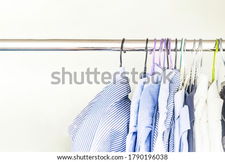 A group of men's shirts of various colors hung with hangers inside a wardrobe. Fashion and clothes.