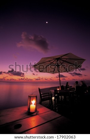 Summer Resort - beautiful glow of the setting sun in tropical island with happy tourists on a background of romantic colorful sky and water