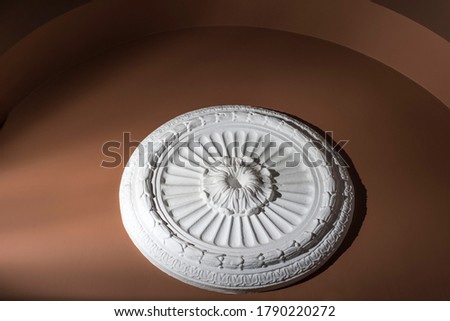 architectural decorative finish on a brown wall, white, round gypsum decorative concrete shield, texture, wall, architectural abstract concrete round