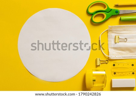 Back to school concept. Office supplies in circle with place for text. Scissors, markers, sharpener, protective medical mask, ruler, notebook arranged in circle.