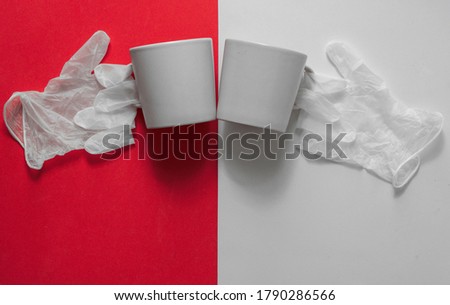 cheers with a cup of coffee. The picture shows coffee cups and the gloves on red and white background.