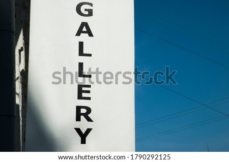 Generic gallery advertisment in form of black text on white banner. Art gallery pointer on a facade. Generic word gallery in form of banner on facade