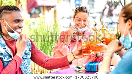 People drinking at cocktail bar with open face mask - New normal friendship concept with happy friends having fun and get out together toasting drink at restaurant - Vivid filter with focus on woman Royalty-Free Stock Photo #1790323700