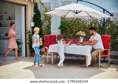 happy kids helping mother to lay up the table at the summer patio, family lifestyle