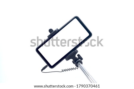 Selfie stick with holding phone on white background.