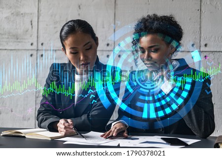 Two businesswomen work together in modern office on new project. Double exposure. Concept of success. Financial graph.