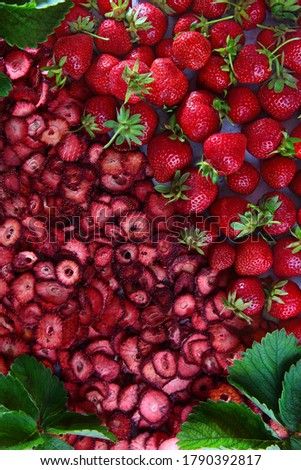 A large number of dried strawberry slices and whole fresh berries. Natural product. Dried strawberry fruit with green leaves. Flat layout. The background photo. Vertical photo.