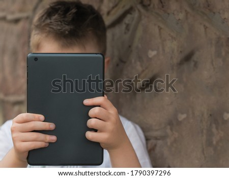 boy with tablet near school with a book online learning boy with tablet in white shirt worth near the walls