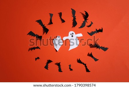 Paper cut Flying bats and ghosts on orange bright background. Halloween background. Top view. Flat lay
