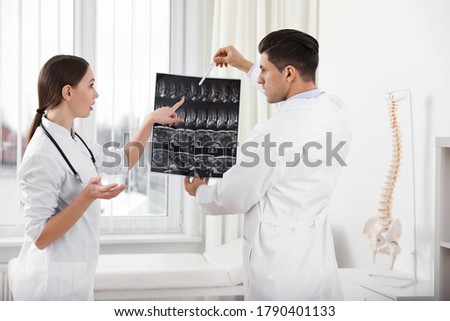 Orthopedists examining X-ray picture near window in office
