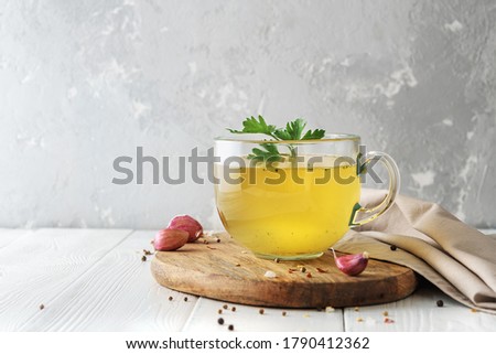 Cup of homemade beef bone broth on white wooden background with a copy of space.