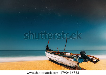 Goa, India. Real Night Sky Stars. Natural Starry Sky Blue Color Above Sea Seascape Ocean Beach. Background. Parked Old Wooden Boat At Coast.