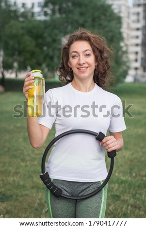 Young sportive woman doing fitness exercises on green grass in warm summer day