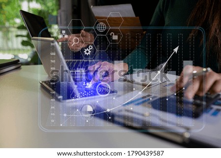 Double exposure of business partners discussing documents and  working on tablet and laptop with digital marketing virtual chart, Business strategy concept, Background toned image blurred.